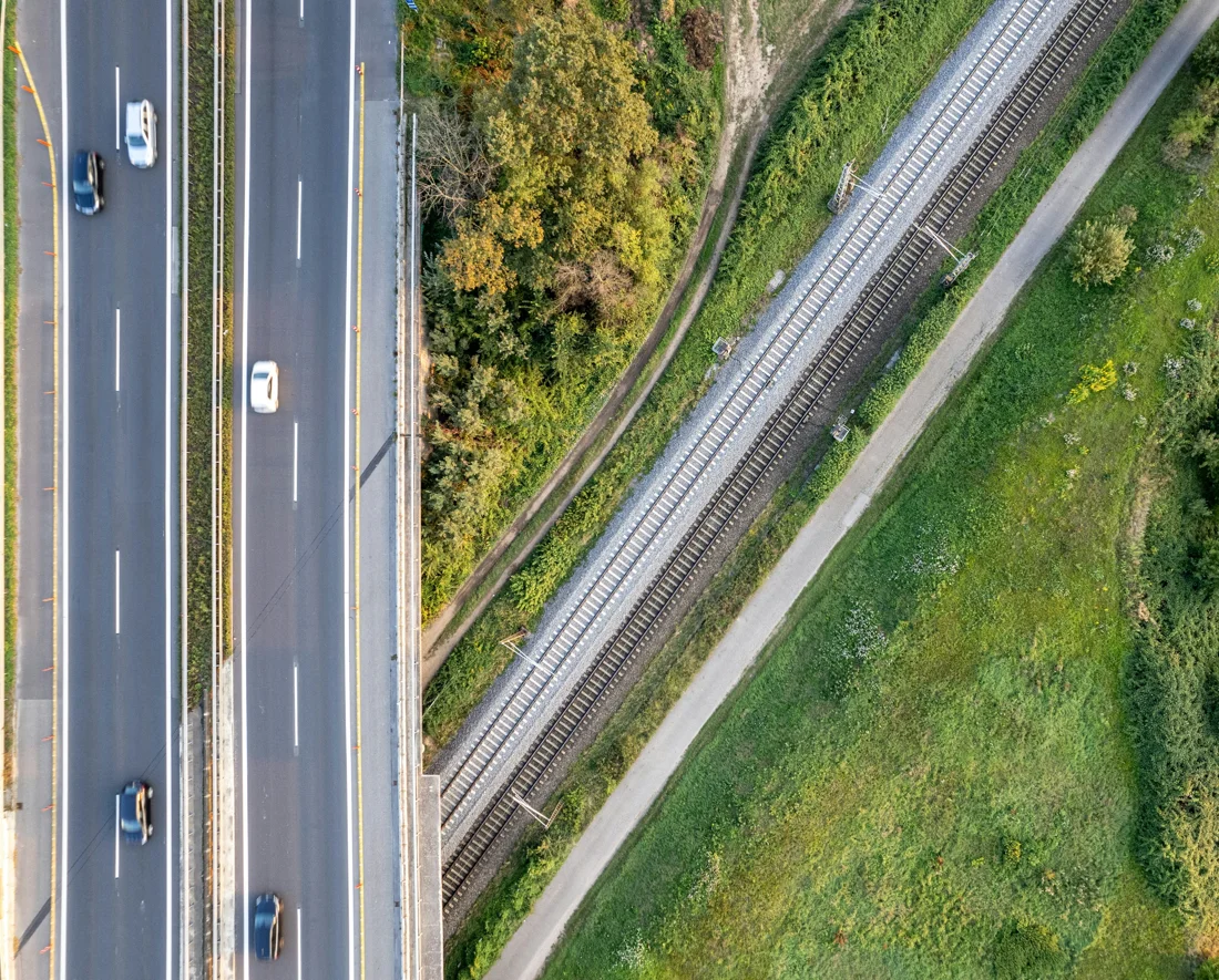 Luftaufnahme einer Straße und angrenzender Bahnstrecke, Symbolbild für Verkehrsinfrastruktur